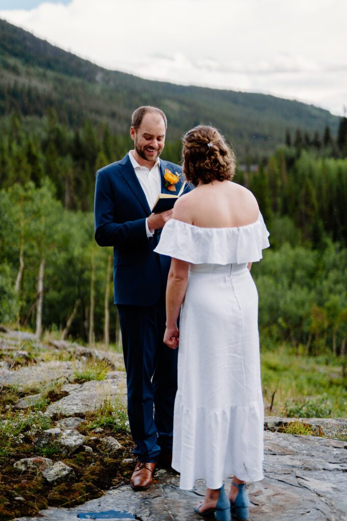 groom smiling and reading his vows to the bride during their eldora mountain colorado elopement