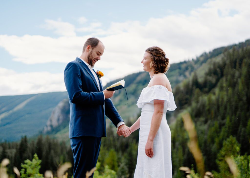 groom holding brides hand as he reads his wedding vows during their eldora mountain colorado elopement
