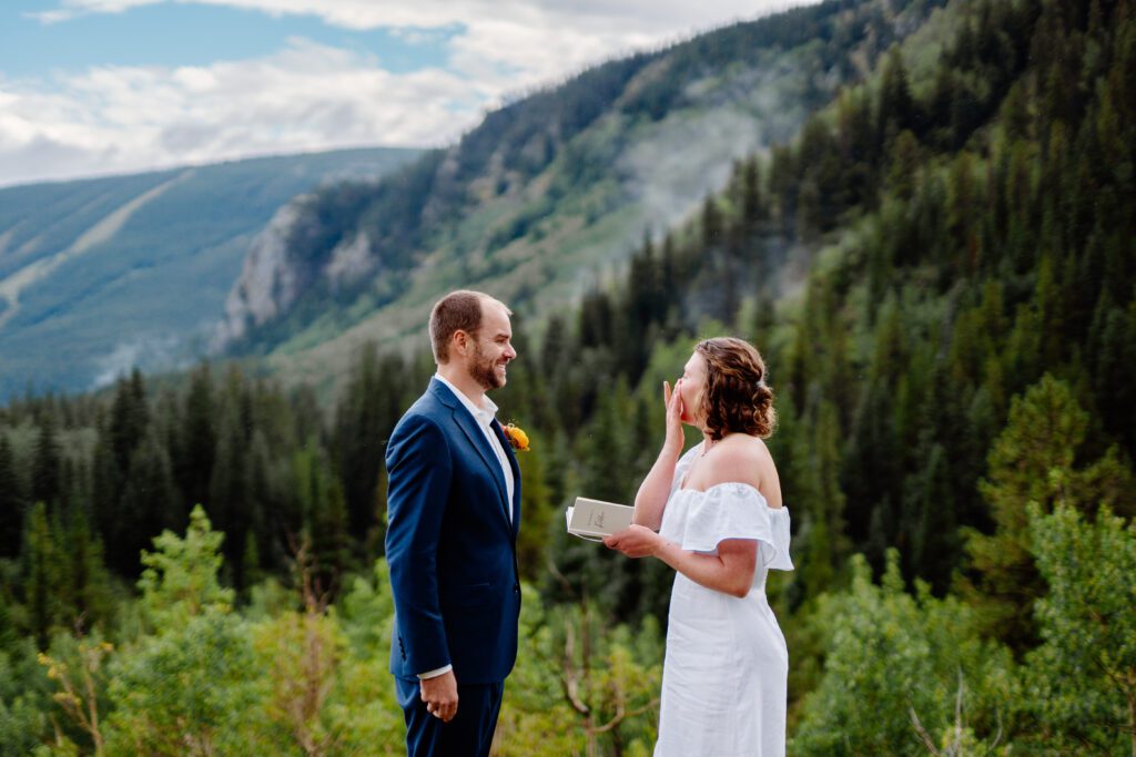 bride wiping away her tears as she reads her marriage vows to her husband during their eldora mountain colorado  elopement