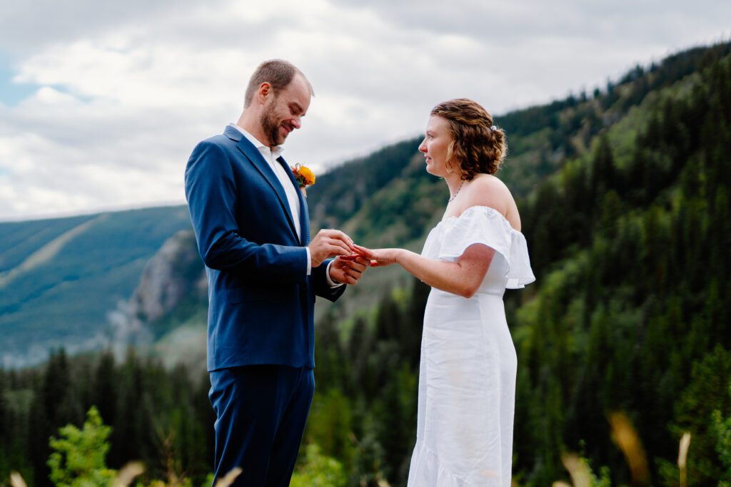 groom placing ring on brides finger during the ring exchange portion of their ceremony at their eldora mountain colorado elopement