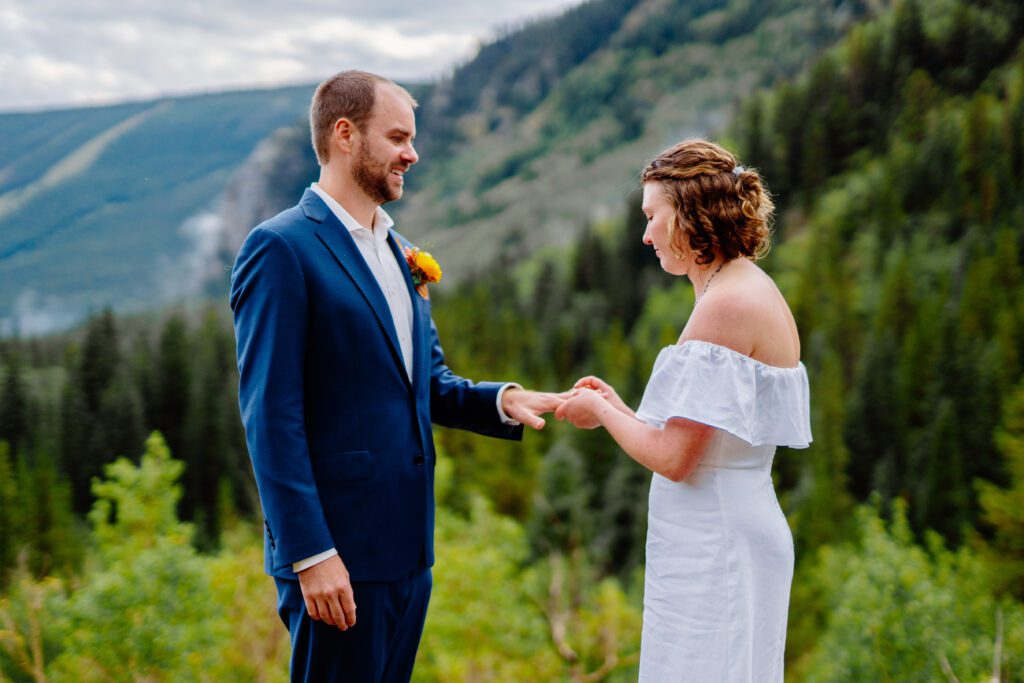 bride placing ring on brides finger during the ring exchange portion of their ceremony at their eldora mountain colorado elopement