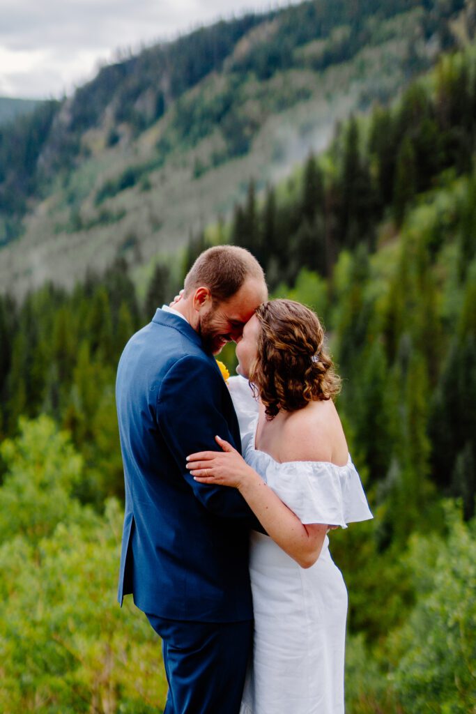 bride and groom touching foreheads and smiling at each other after their first kiss during their eldora mountain colorado elopement