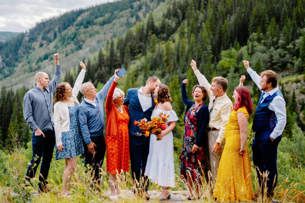 bride and groom kissing as their family cheers for them during their eldora mountain colorado elopement