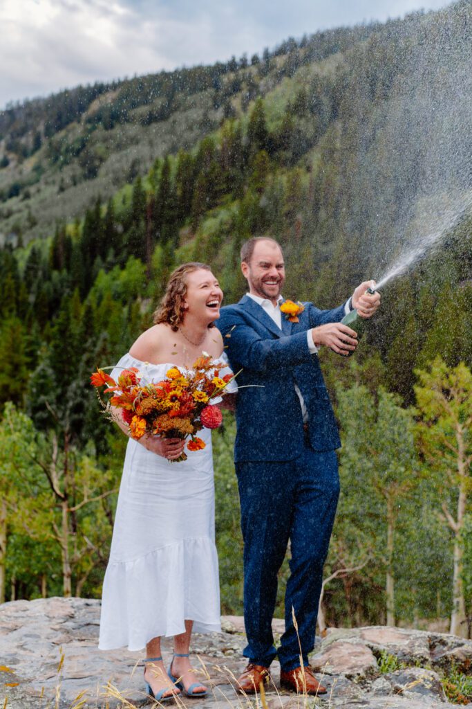 bride and groom on spraying champagne in celebration of their marriage during their eldora mountain colorado elopement