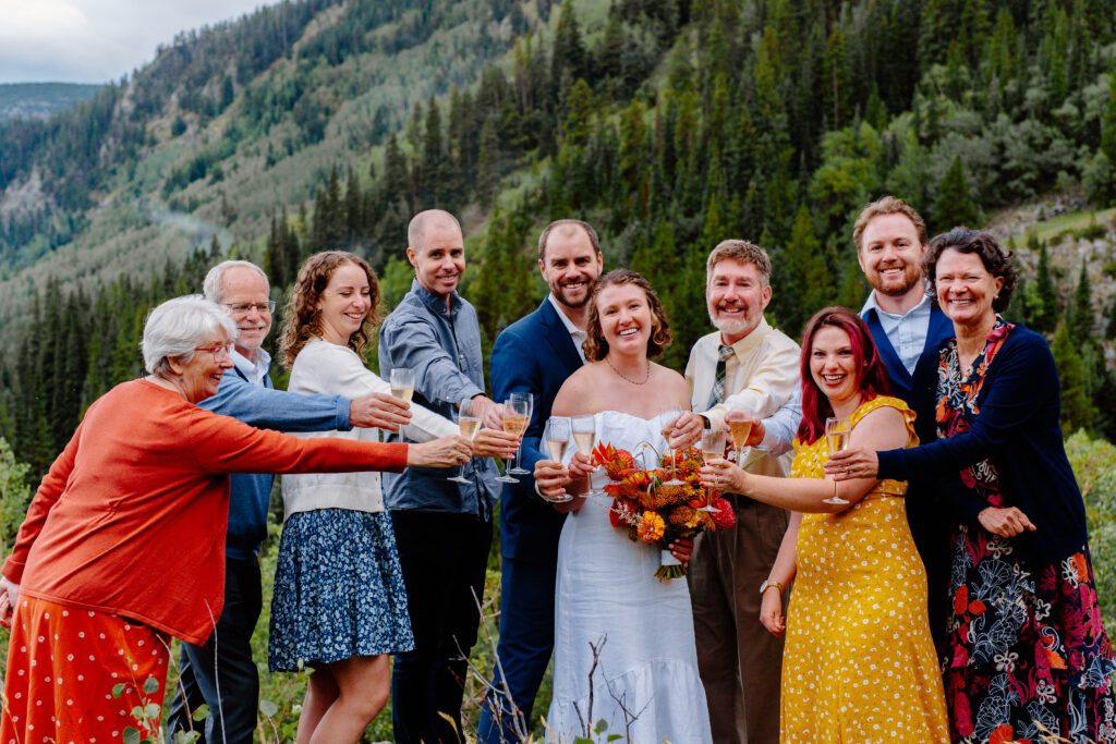 bride and groom toasting champagne with their guests on top of a mountain during their eldora mountain colorado elopement