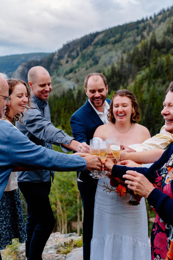 bride and groom cheersing with guests at their eldora mountian colorado elopement