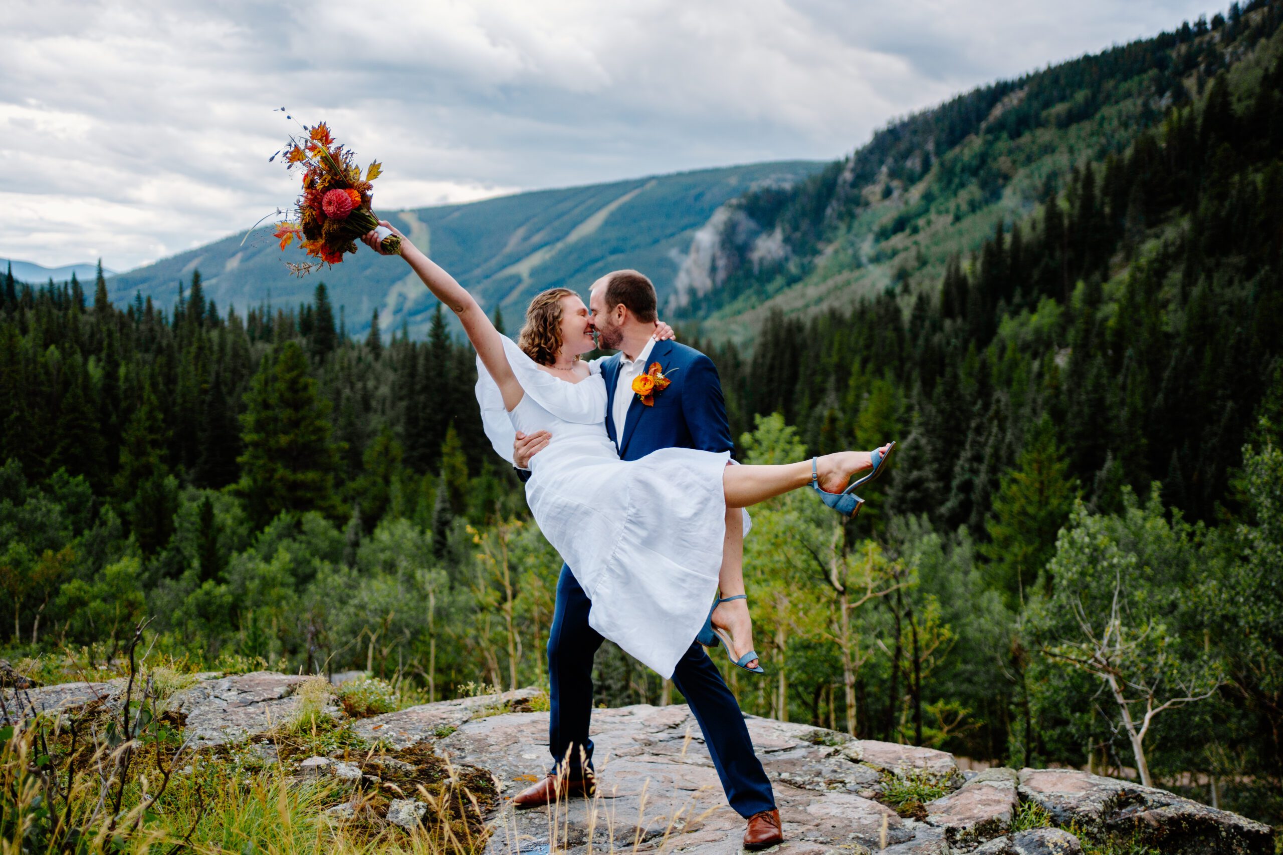 bride and groom standing on mountain cliff after their private elopement ceremony at eldora mountain colorado