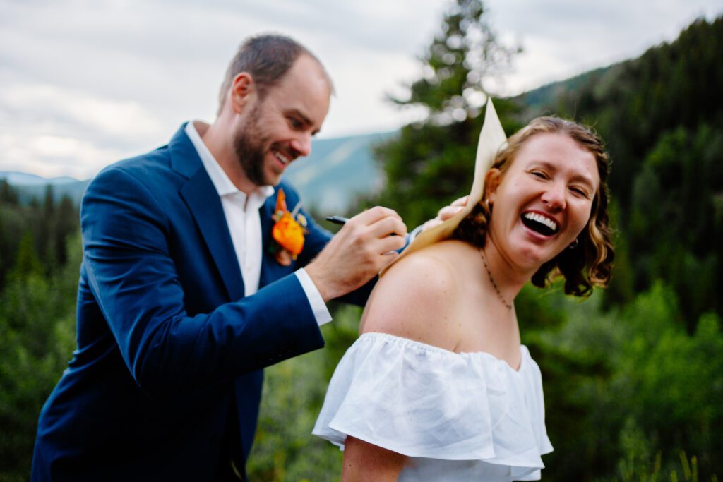 groom signing the marriage license on the brides back during their eldora mountain colorado elopement