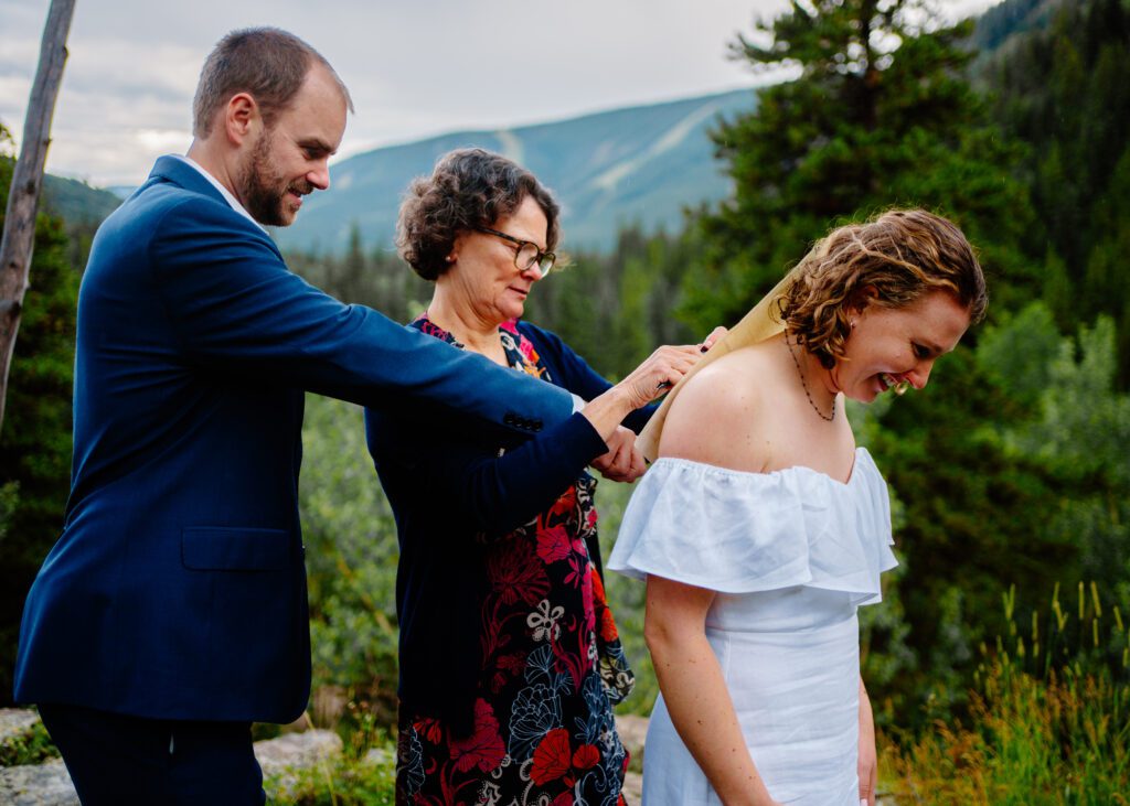 mother of the bride signing the bride and grooms marriage license on her back during their eldora mountain colorado elopement