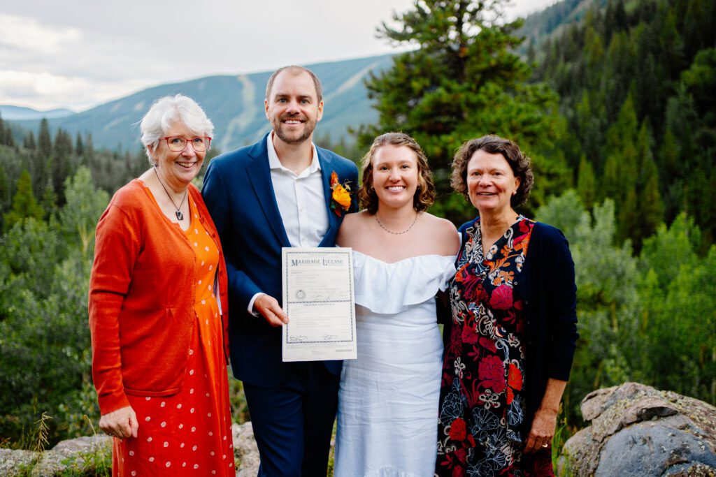 bride and groom with their moms holding the marriage certificate they just signed during their eldora mountain colorado elopement
