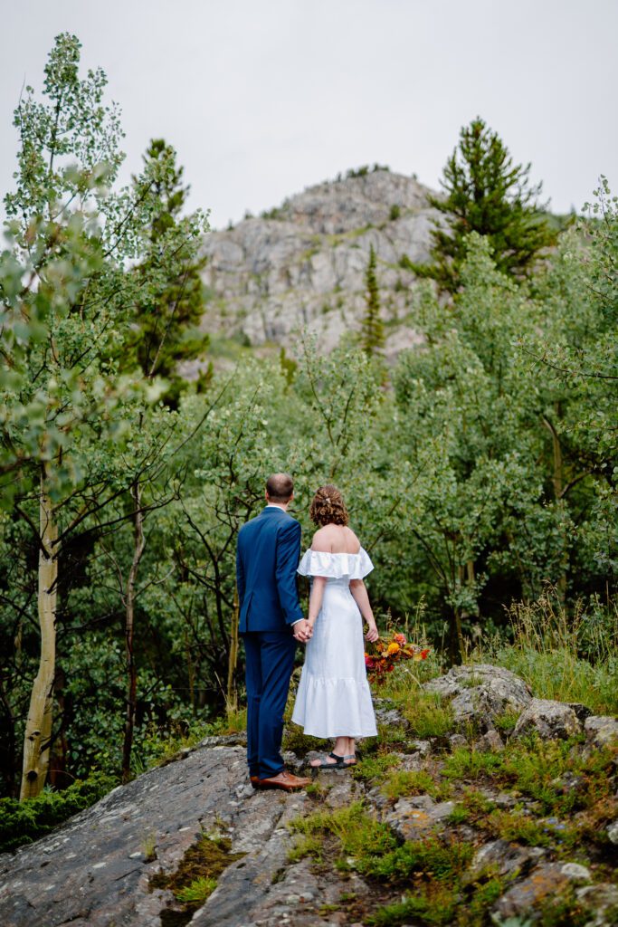 bride and groom holding hands looking at eldora mountain colorado during their elopement