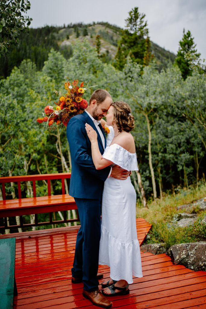 bride and groom standing on the back porch of their family cabin at their eldora mountain colorado elopement
