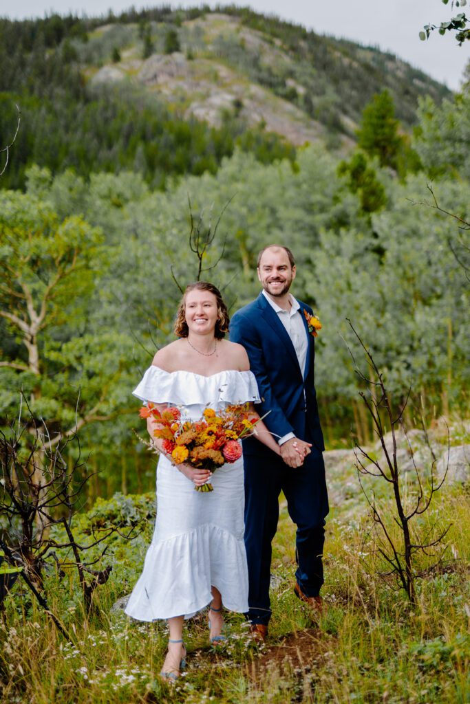 bride and groom walking up the mountan towards their ceremony on eldora mountain colorado for their elopement
