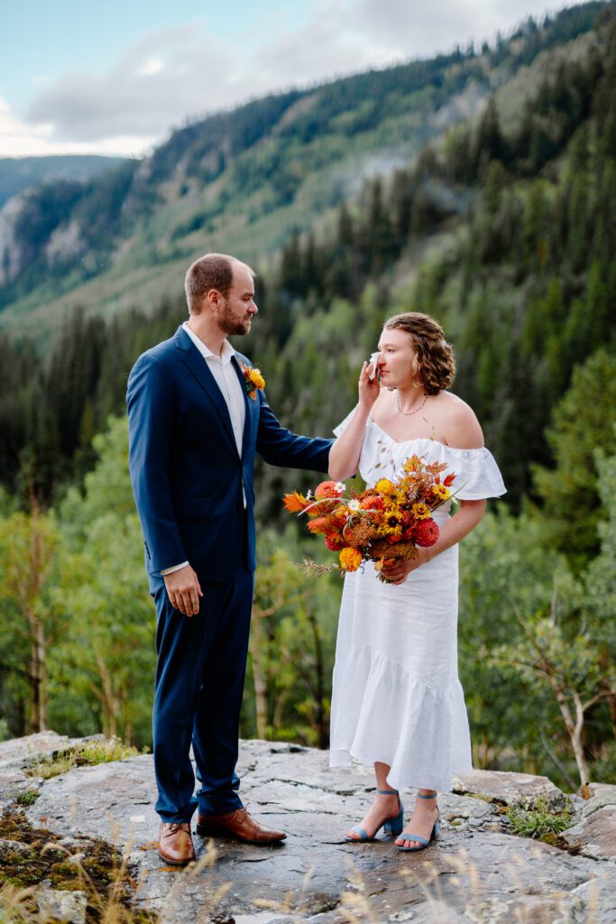 bride wiping tears away during her eldora mountain colorado elopement at her family cabin