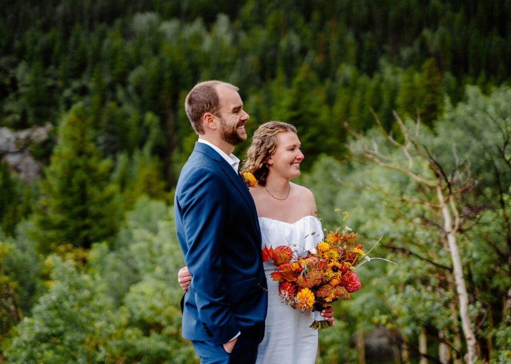 bride and groom smiling during their elopement ceremony as their family reads statements about their love story at eldora mountain colorado