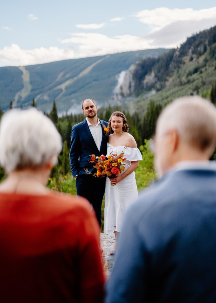 bride and groom looking at his parents as they read a statement during their eldora mountain colorado elopement