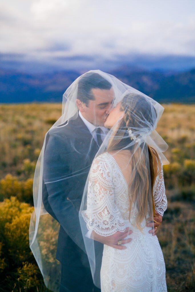 bride and groom standing under her veil during their colorado springs elopement