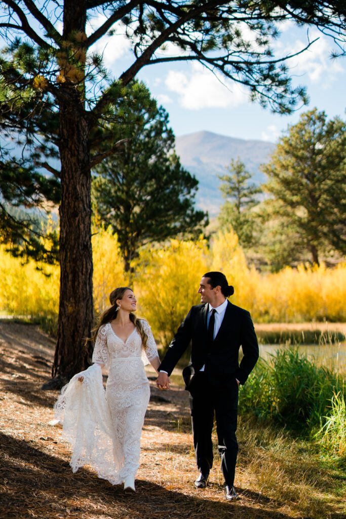 bride and groom holding hands walking through the forest during their colorado springs elopement