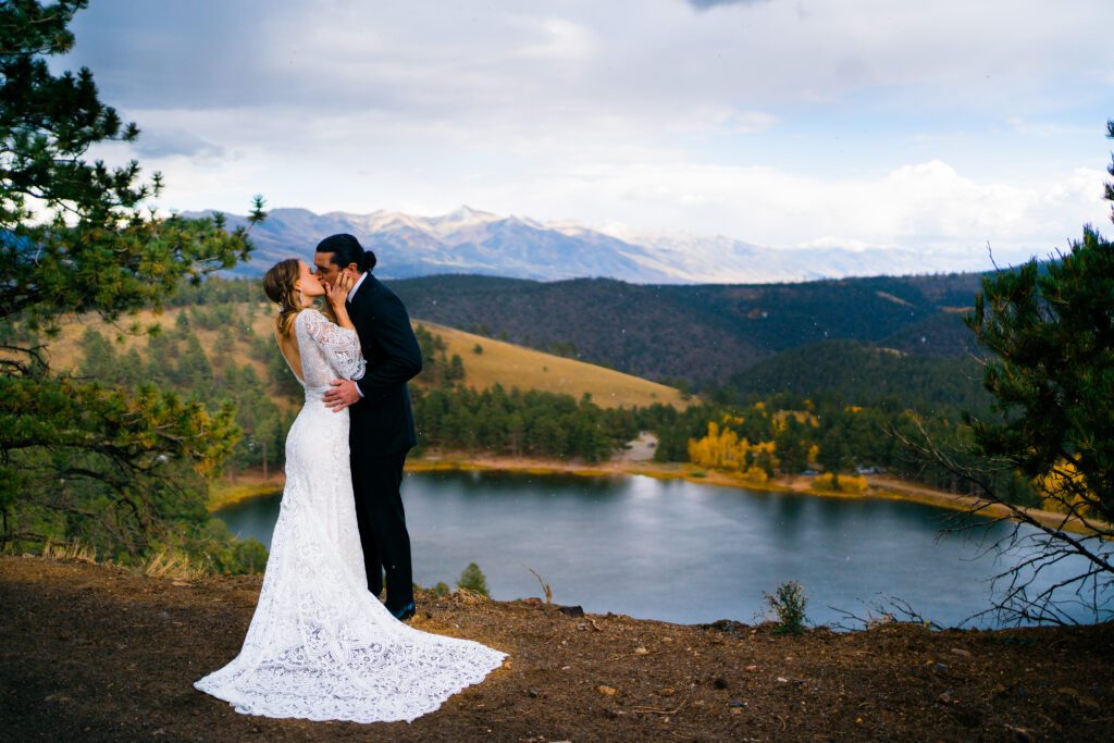 bride and groom kissing on a cliffside looking out over a lake during their colorado springs elopement
