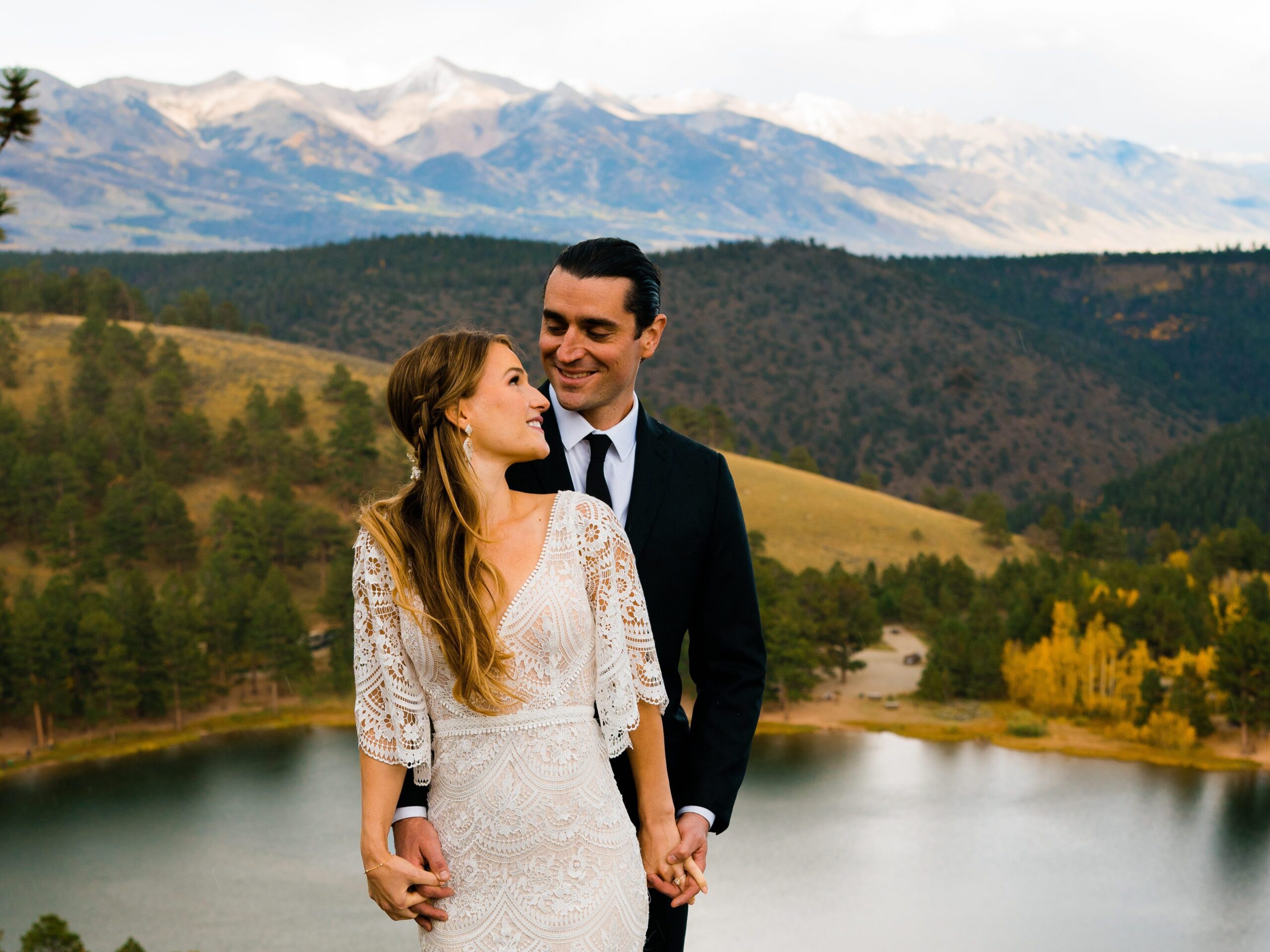 bride and groom holding hands and smiling at eachother in front of the crestone mountains during their colorado springs elopement