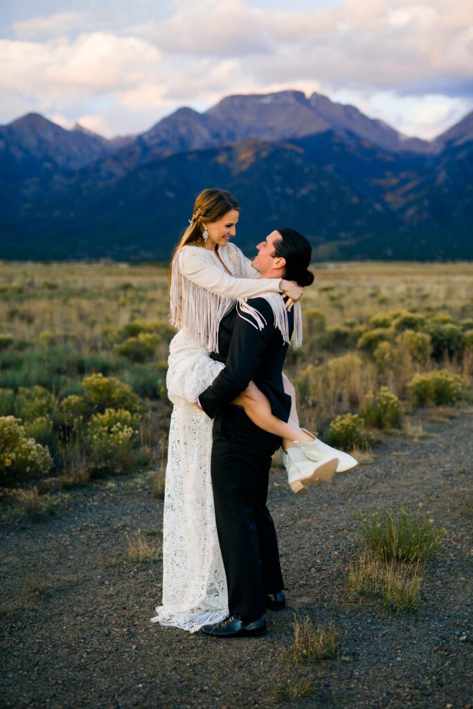 groom lifting bride off the ground smiling at her with the mountains in the background during their colorado springs elopement
