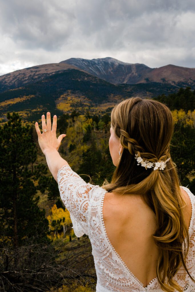bride holding her hand up in front of the mountain while looking at her ring