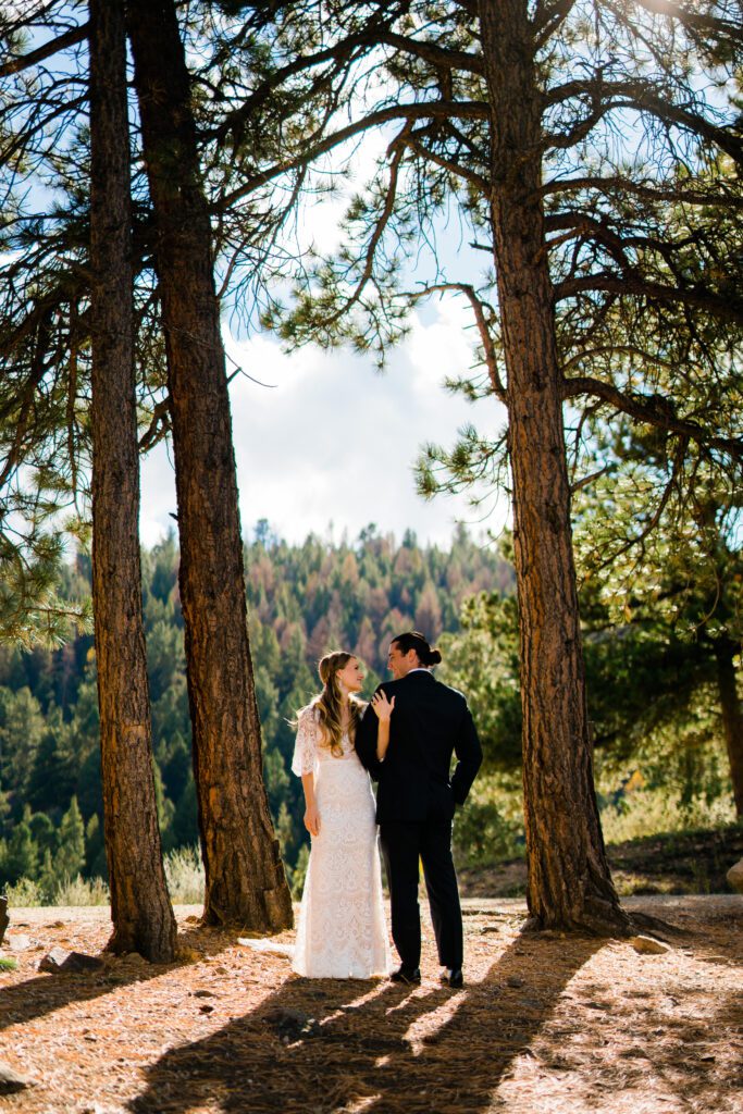 bride and groom standing between two trees smiling at eachother during their colorado springs elopement
