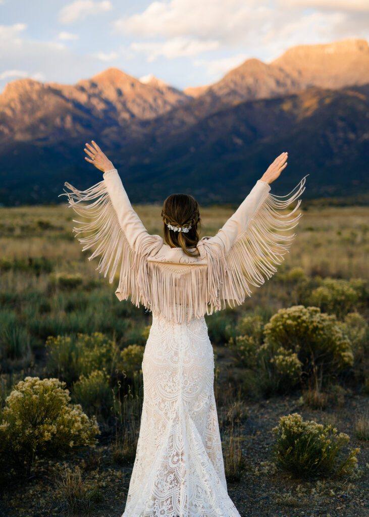 bride facing away from the camera wearing a fringe jacket during her colorado springs elopement