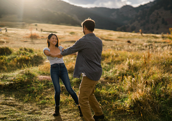 engaged couple spinning each other around at Chautauqua park in boulder Colorado