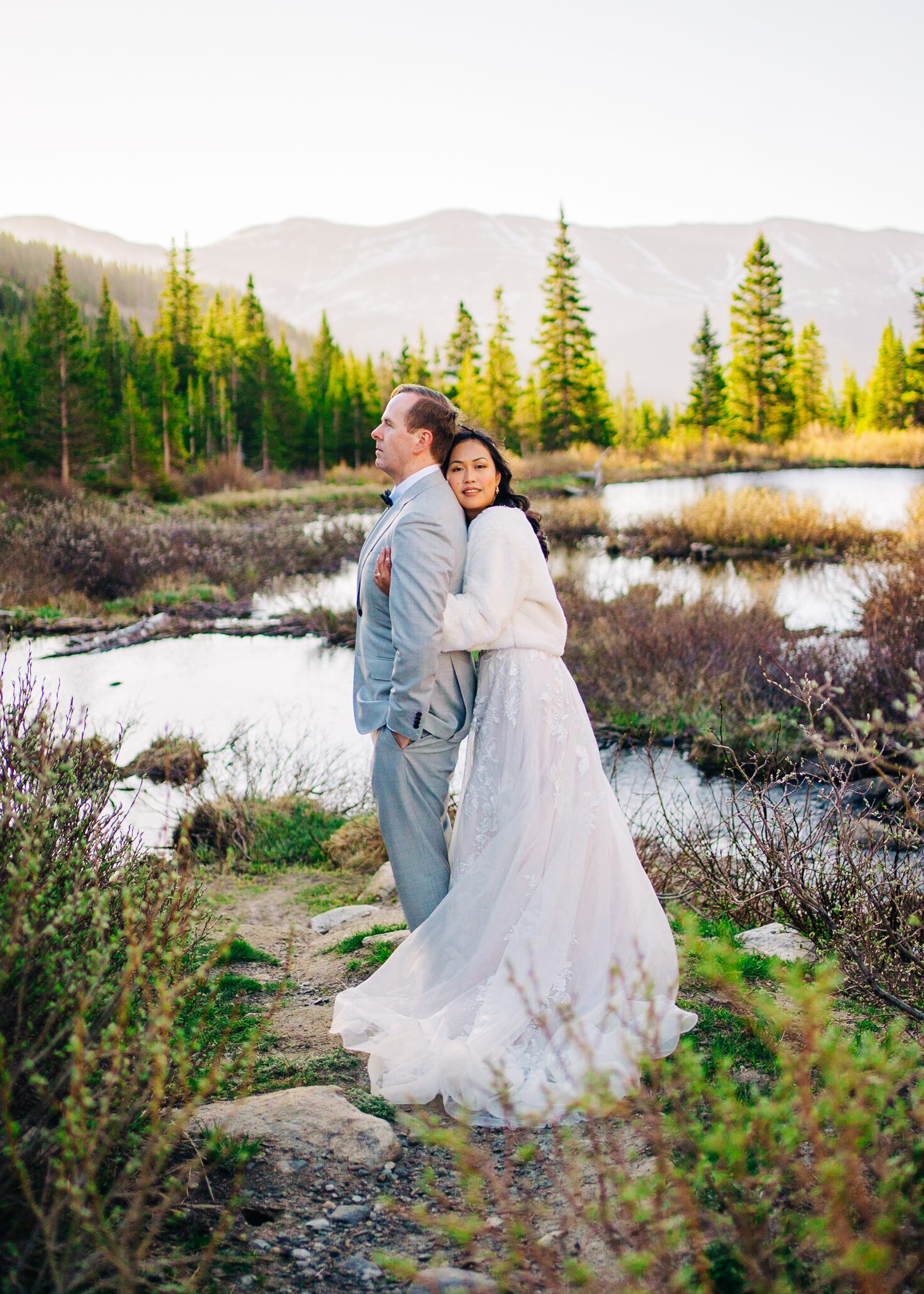 bride hugging groom from behind as she smiles at the camera during their colorado breckenridge elopement