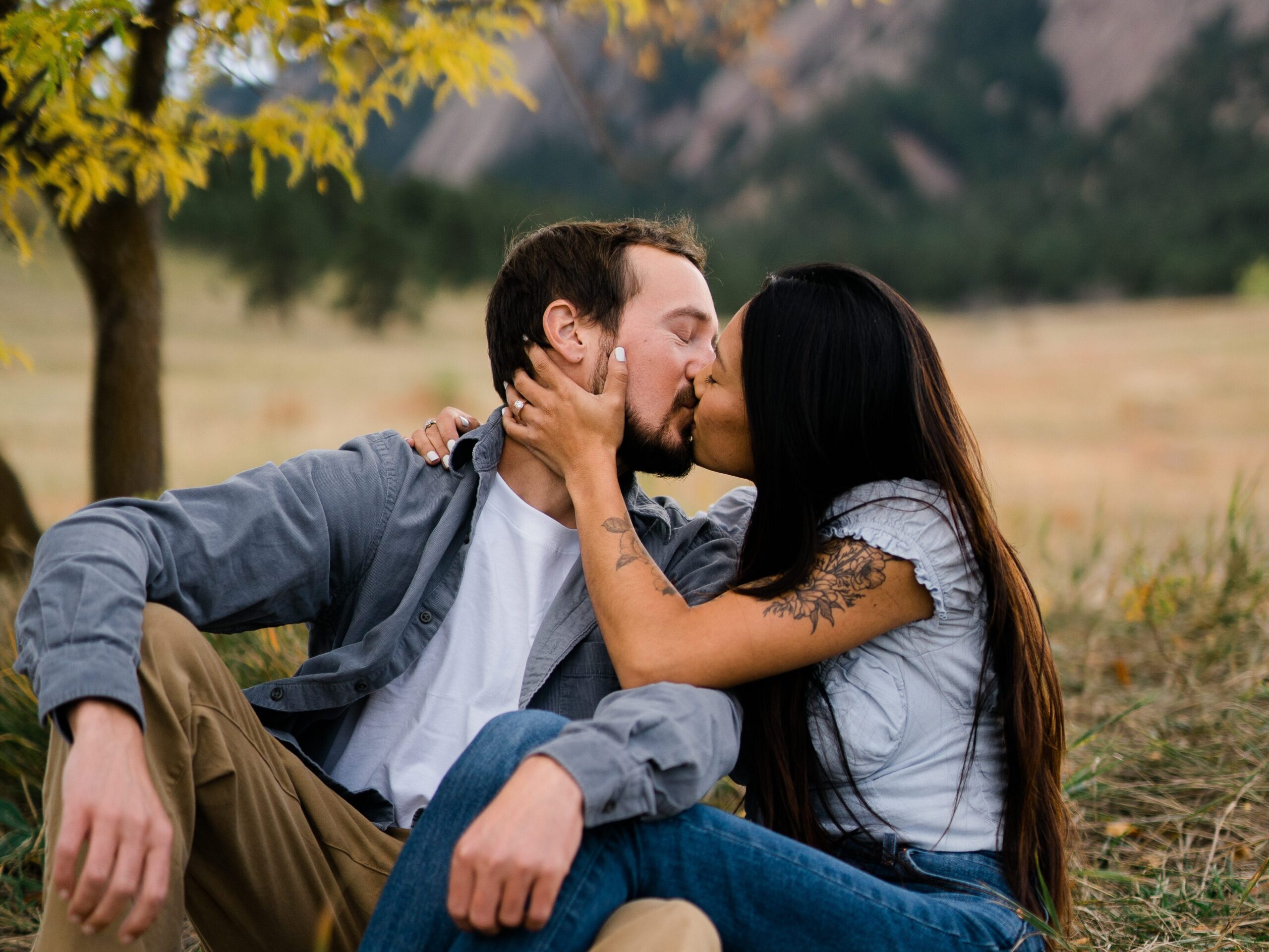 engaged couple sitting in a field during their Chautauqua Park Engagement Photos