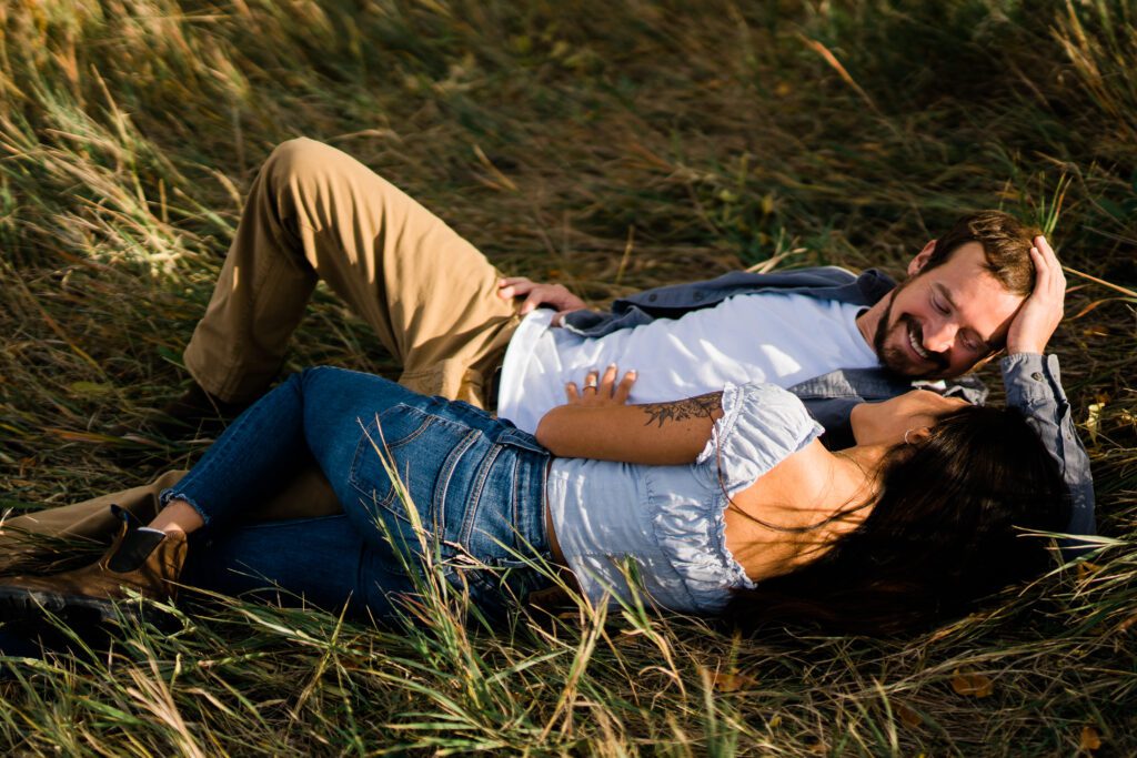 engaged couple laying in tall grass together during their Chautauqua Park Engagement Photos