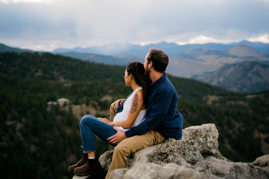 engaged couple sitting on a mountain edge at lost gulch in boulder colorado during their engagement photos
