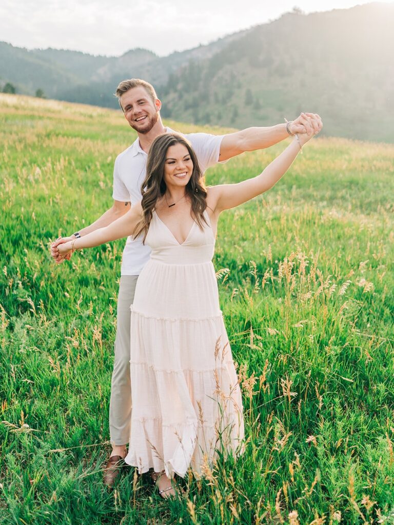 boyfriend and girlfriend holding hands in a field at chautauqua park during their couples session in boulder colorado