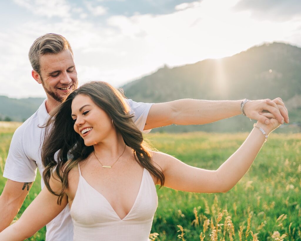 boyfriend and girlfriend holding hands and smiling at the camera during golden hour at their boulder colorado couples session at chautauqua park