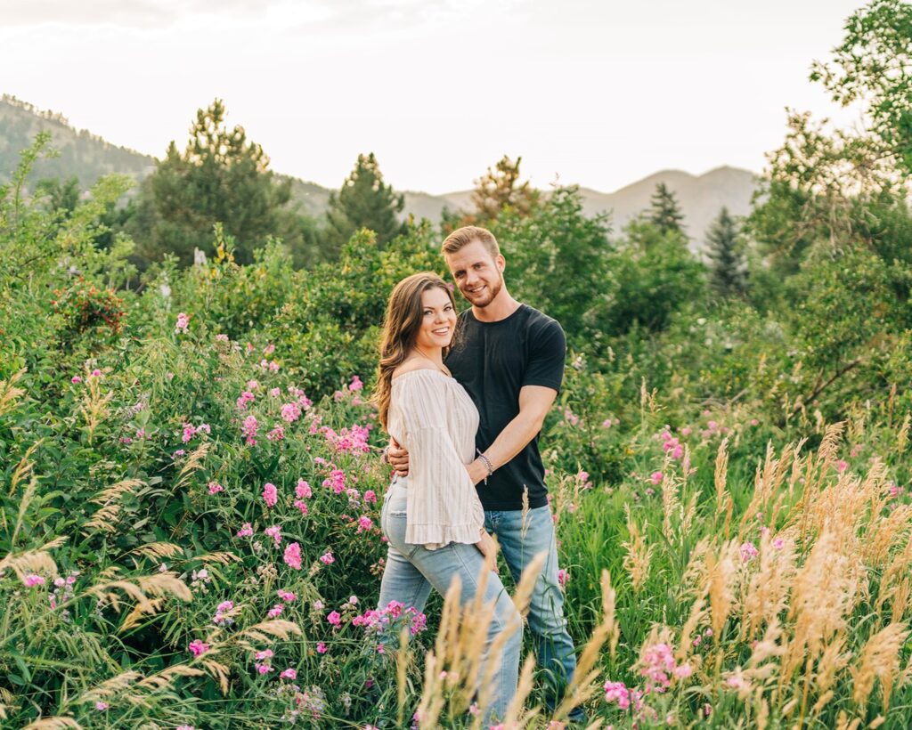 cute couples standing in a wild flower field in chautauqua park during their boulder colorado engagement session