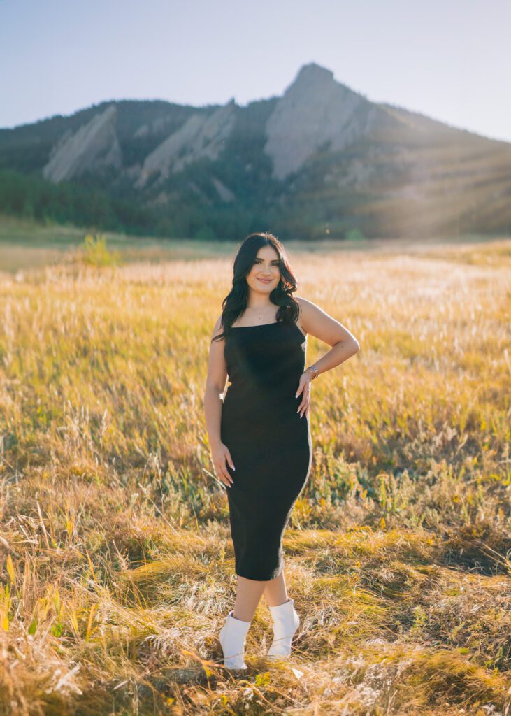 photo of a beautiful latina women standing in a field wearing  a black dress at Chautauqua park in boulder colorado