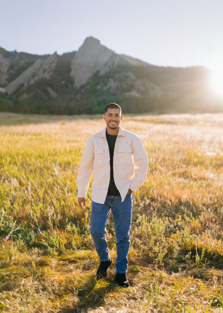 handsome latina man walking through a field at Chautauqua park in boulder colorado