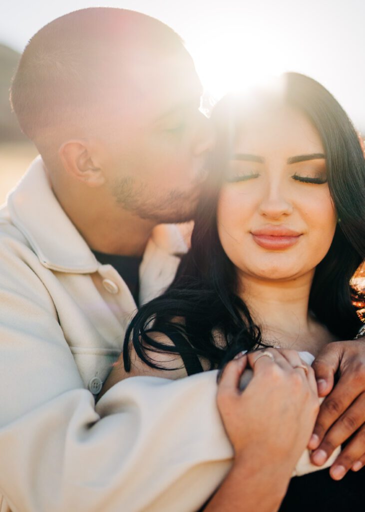 boyfriend kissing his girl friends temple during golden hour at lost gulch overlook in boulder colorado during their couples photoshoot