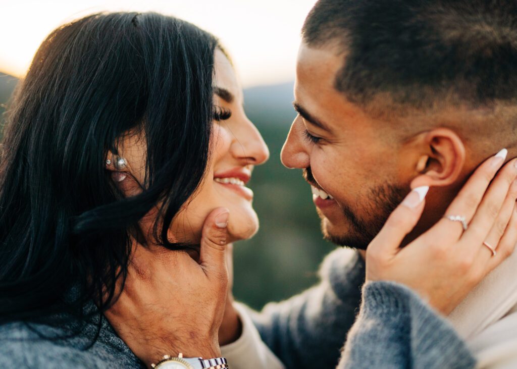 cute couple smiling at eachother before they are about to kiss during their couples photoshoot at lost gulch overlook in boulder colorado