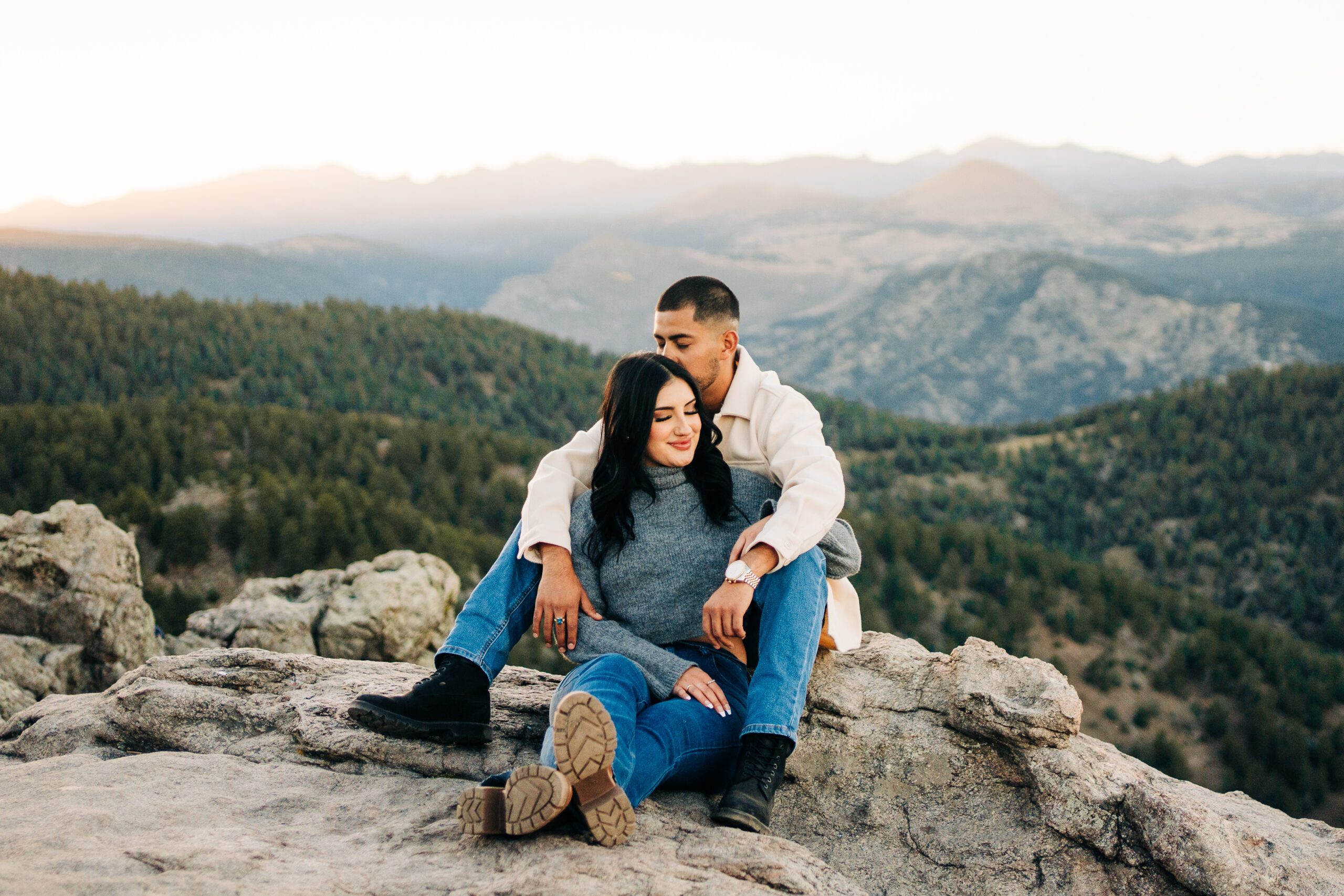 cute couples sitting on the cliff edge at lost gulch overlook in boulder colorado during their couples photoshoot