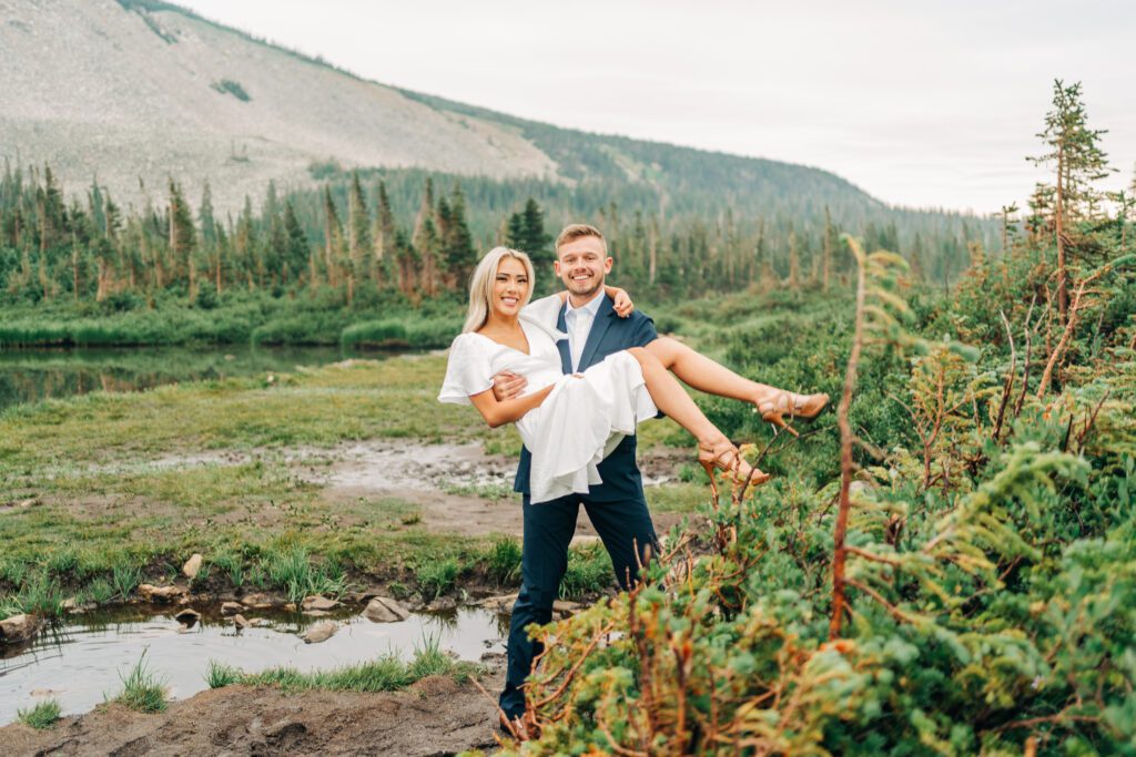 Groom holding the bride while they both smile at the camera with Lake Mitchell in the background during their colorado elopement at Brainard Lake Recreation Area
