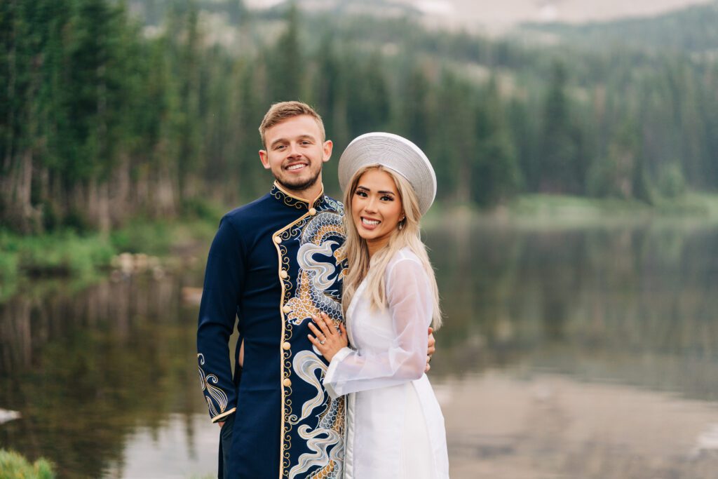 bride and groom hugging while smiling at the camera while wearing traditional vietnamese wedding attire during their colorado elopement