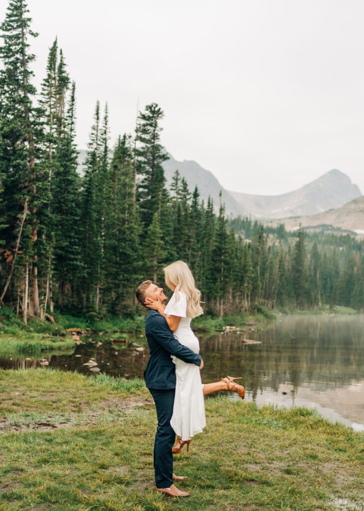Groom picking up bride and looking at her during their elopement at Brainard Lake Recreation Area. Photo taken at Lake Mitchell.