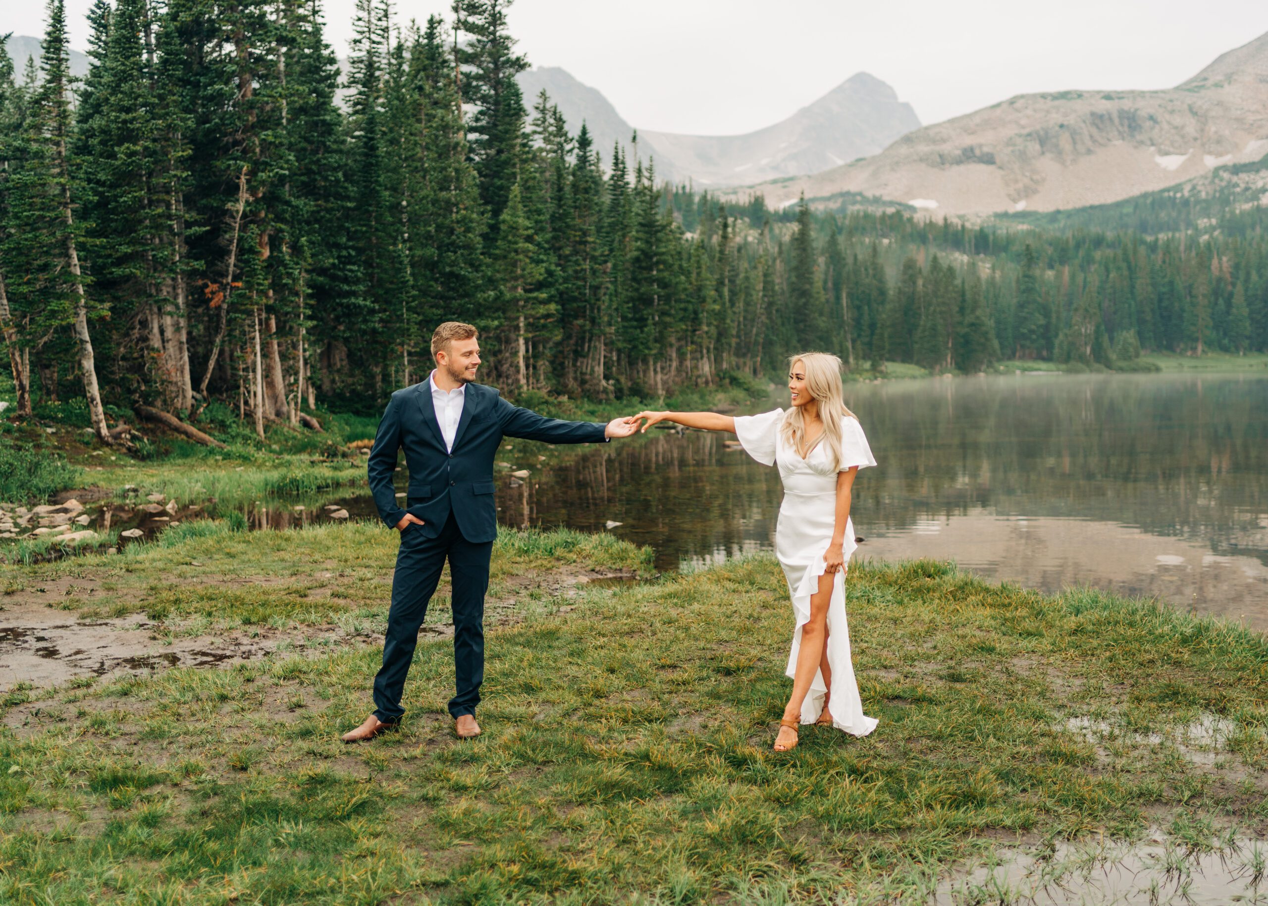 bride and groom holding each others hands while standing in front of Mitchell Lake during their Brainard Lake Elopement in Colorado