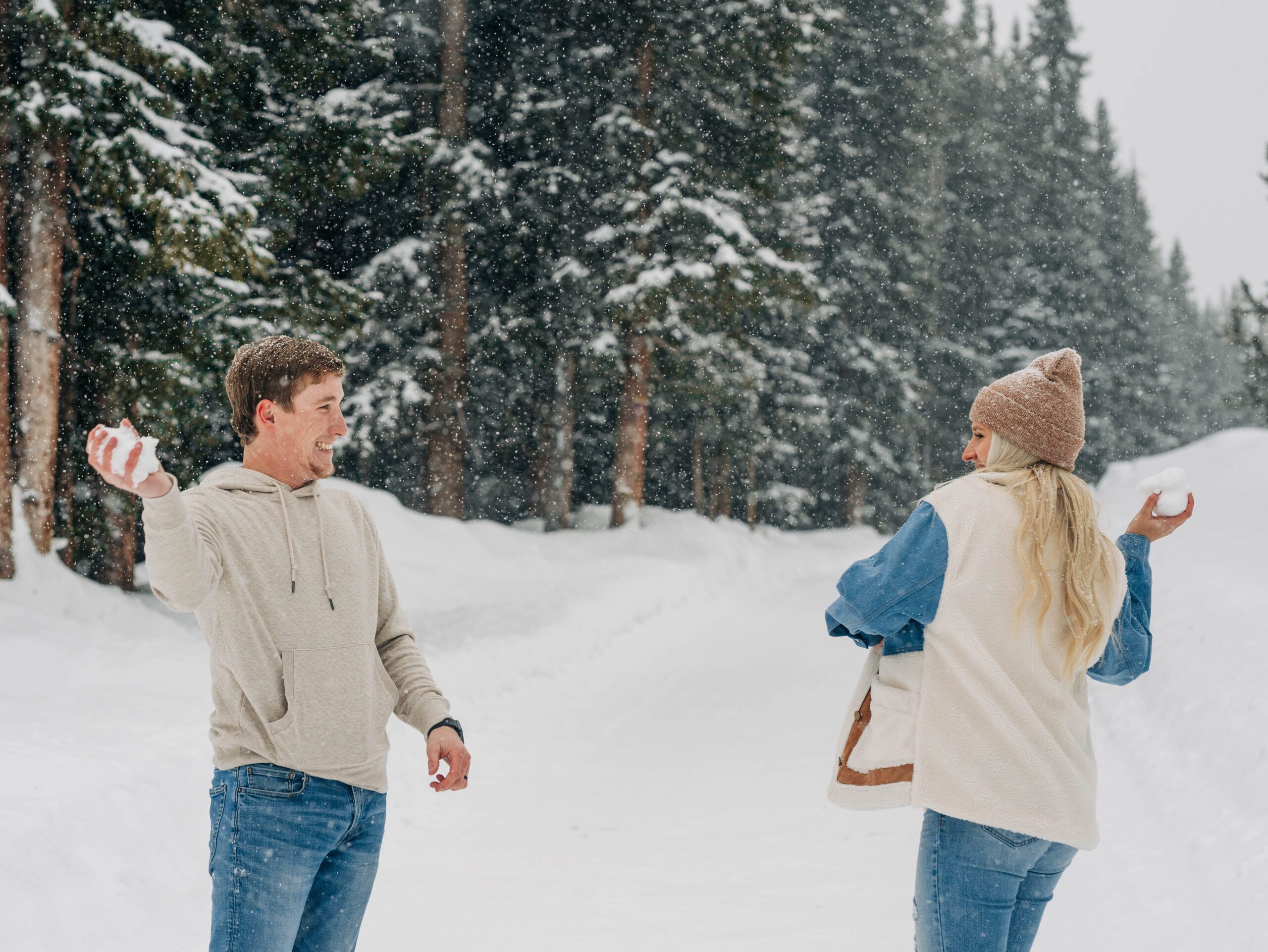 cute couple having a snowball fight during their winter breckenridge engagement session