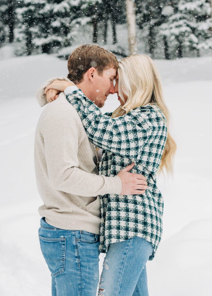 cute couple with their foreheads pressed together while standing in the snow during their breckenridge engagement session