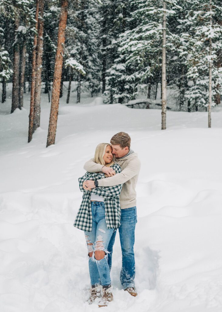 husband wrapping wife into a big bear hug during their snowy breckenridge engagement session