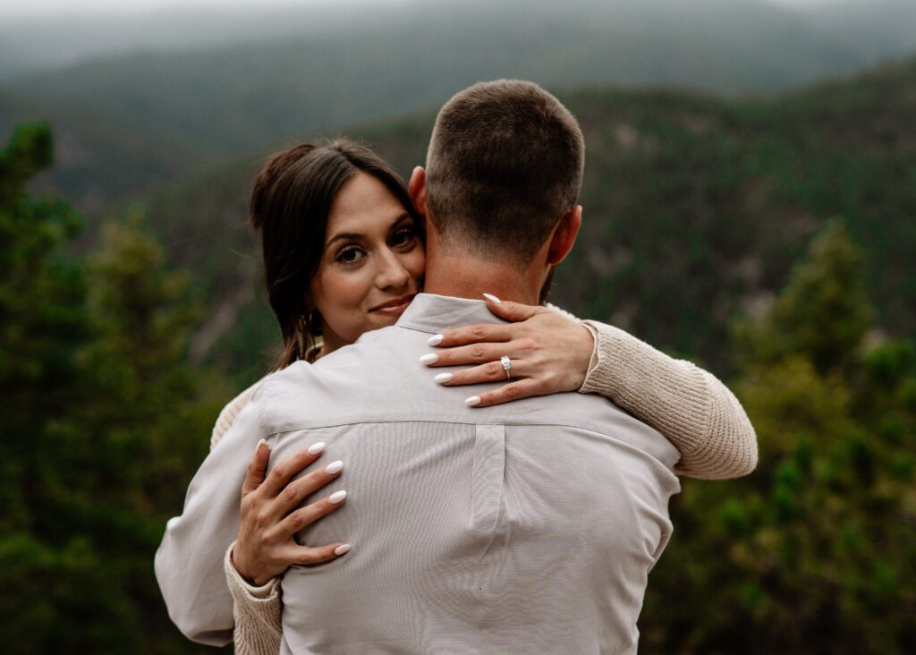 girl looking at the camera while hugging her fiance during their proposal in colorado