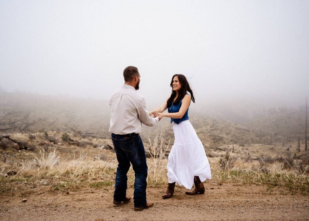 finace swinging his girlfriend around in a field smiling during their proposal in colorado